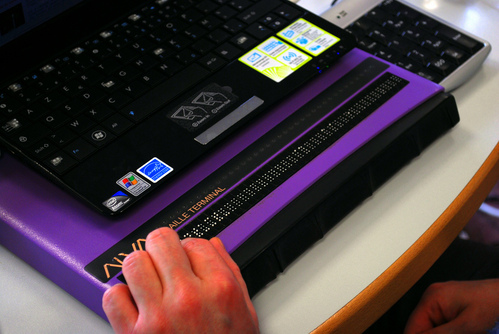 A purple machine with a sequence of braille characters in raised pins along the front row.