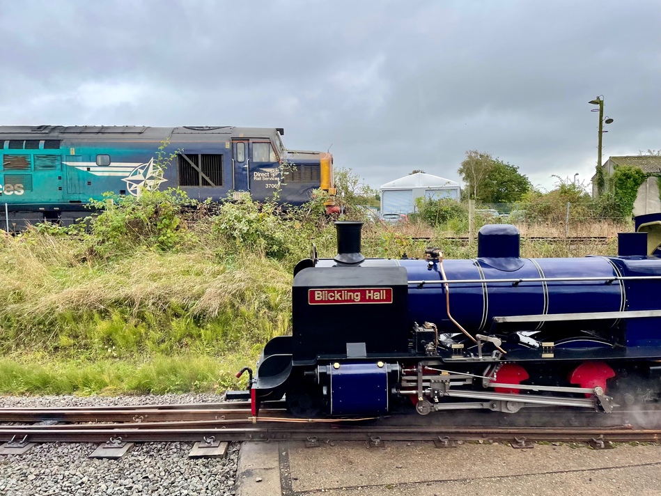 A profile shot of the dark blue tender engine and a large blue/turquoise diesel engine heading in the opposite direction on the track above.