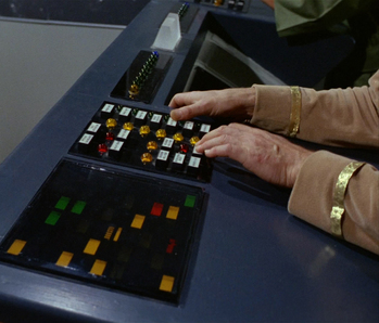 Two panels of coloured lights and buttons on a spaceship console. We can see somebody in a gold uniform reaching out to push the buttons.