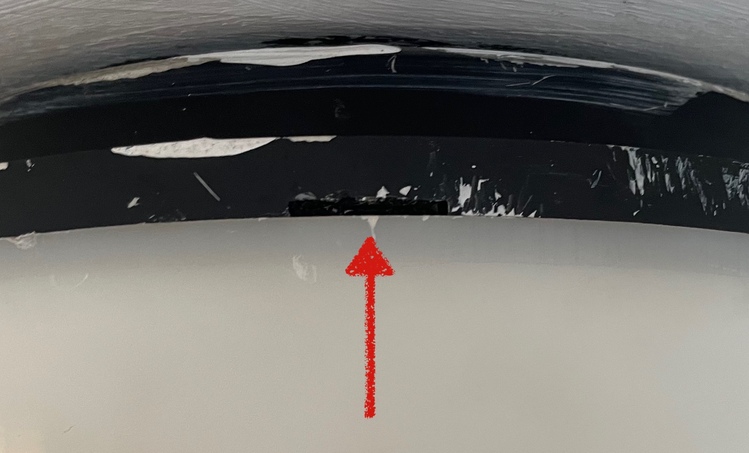 A close-up photograph of where the base meets the cover. There's a gap in the base, with a red arrow pointing to it.