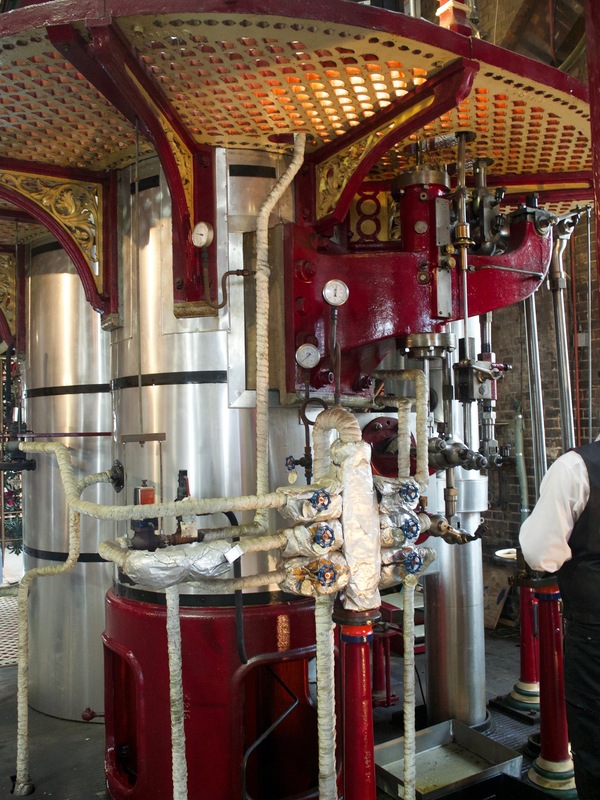A series of pipes and tubes surrounding cylindrical boilers. Some of the metalwork has red and gold decorations.