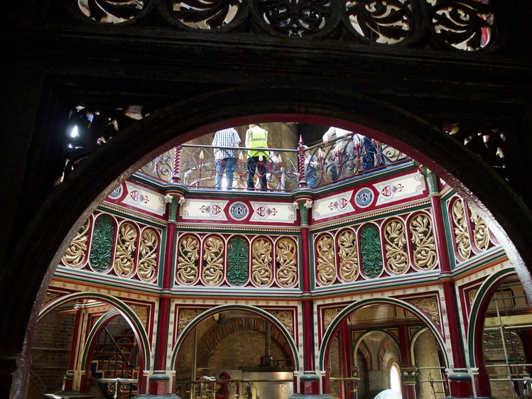 Dark arch, an octagonal gap in the ceiling looking up to the next level. The gap is decorated in gold, red and green metalwork.