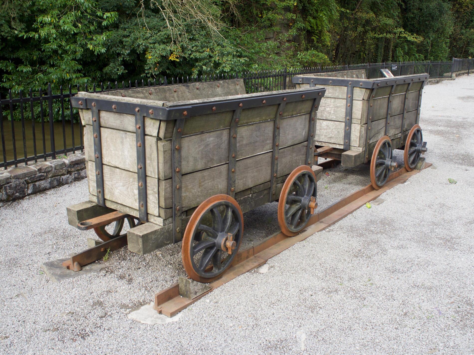 A pair of wooden carts on rusted railway tracks.