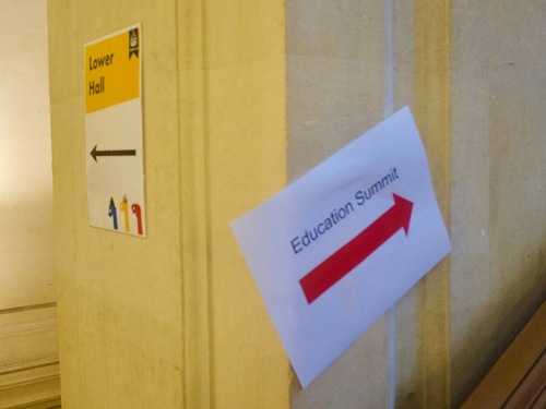 A pillar with a white-and-yellow sign labelled “Lower Hall” on one side, and a sign with a red arrow labelled “Education Summit” on the right.