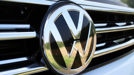 A close-up badge of a Volkswagen badge on a car’s radiator grille.