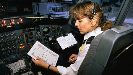 A pilot inspecting a checklist in the cockpit of a plane.