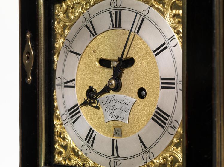 A clock face with Roman numerals and gold decoration.
