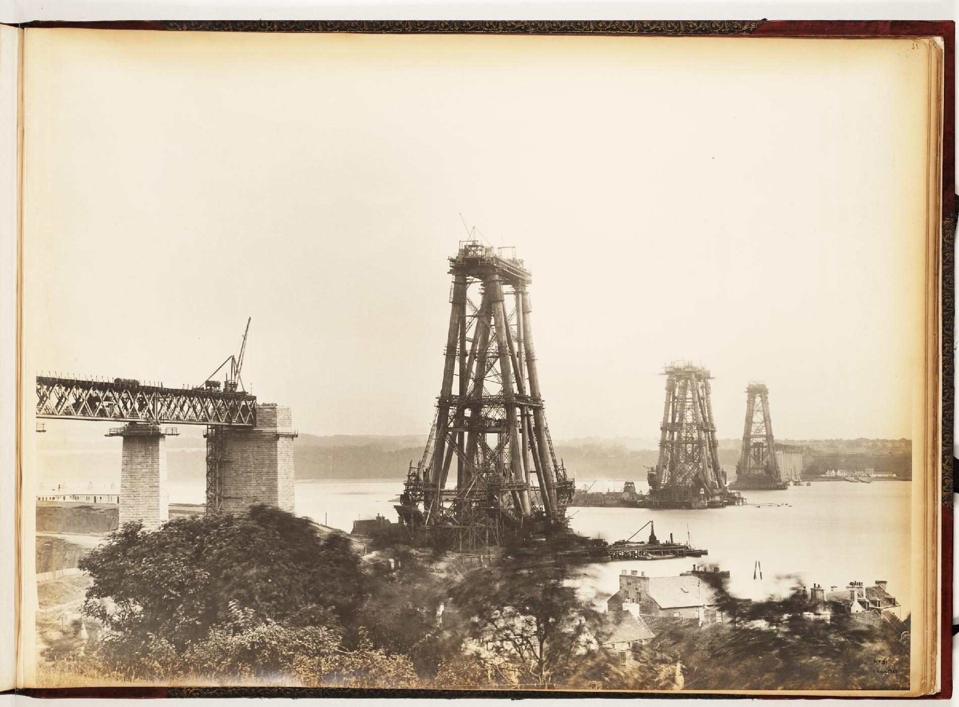 A sepia-toned photograph of a partially constructed bridge, with three cantilevers visible above the water.