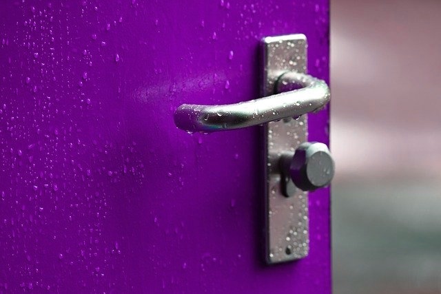 A metal door handle on a purple door