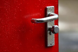 A metal door handle on a red door