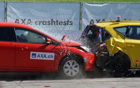 A red car (left) crashing into the back of a yellow car (right).