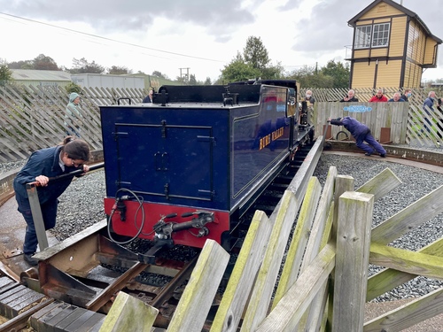 A dark blue engine sitting on the turntable. This is larger than the black engine, and it's taking two people pushing to turn it around. It looks like quite a strain!