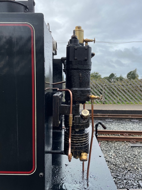 A close-up of some weird gizmo on the side of the black train. There are copper pipes and coils and brass valves… I have no idea what it does, but it looks cool!