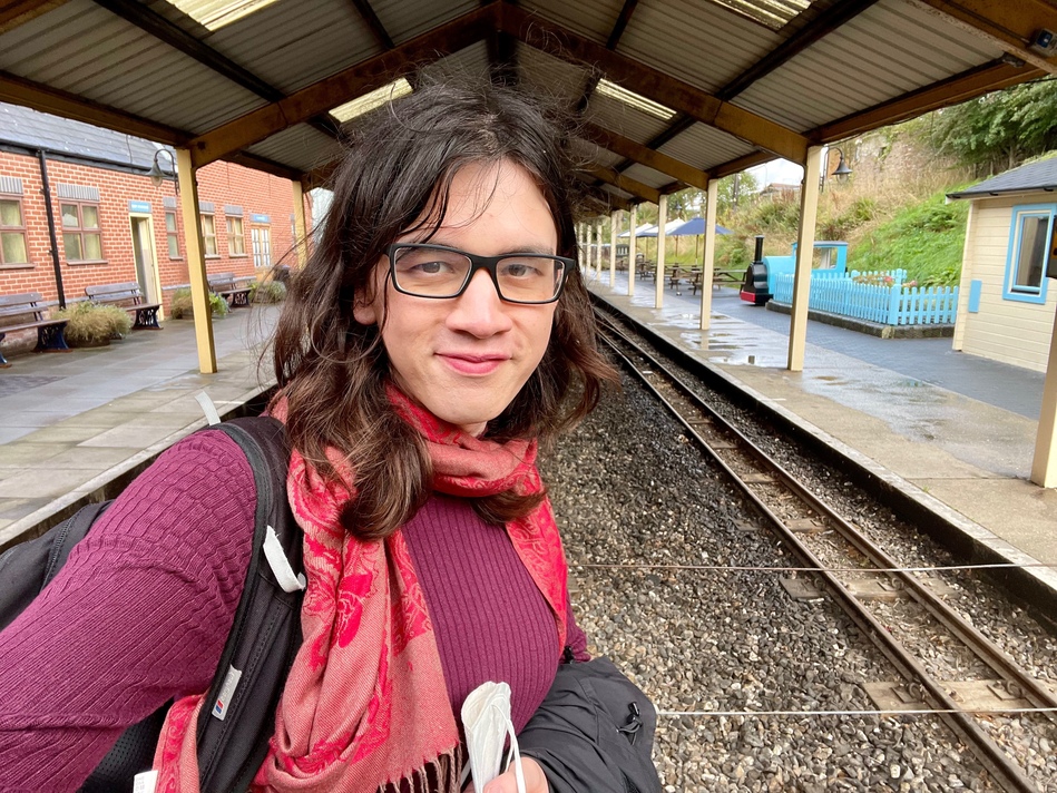 Another selfie! I’m a bit dishevelled, my hair is ruffled, and my hands are full of stuff. I’m standing in front of the station canopy, and I’m beaming. Huge smile.