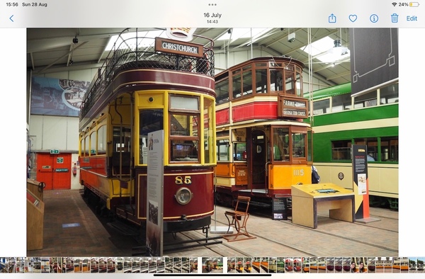 Screenshot of the iPad photos app. The photo of the two trams takes up most of the screen, with a toolbar along the top and a carousel of small thumbnails along the bottom. The carousel images are all tall and narrow, and tightly scrunched together.