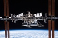 The International Space Station, a collection of silver tubes and panels, floating in space above the Earth.