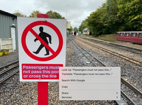 A picture of a railway sign with the text highlighted, and a popover menu offering several options: ‘Look up “Passengers must not pass this point or cross the line”’, ‘Translate “Passengers must not pass this point or cross the line”’, Search with Google, Copy, or Share.