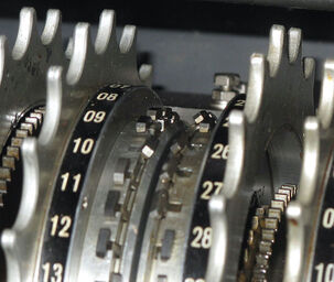 A close-up photo of two metal wheels. The wheels have numbers running around the rim, and next to each number is a small metal switch.