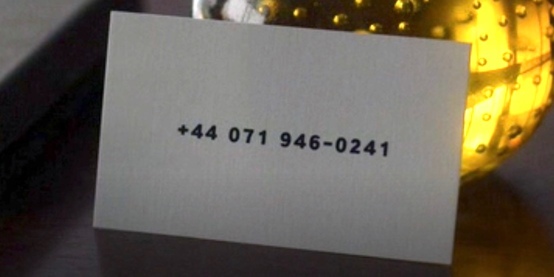 Close-up shot of a plain white business card with the number '+44 071 946-0241'. The number is written in black text, with no other markings on the card.