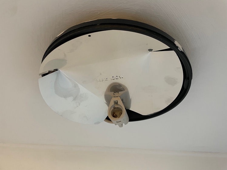 Just the base of the light, with the cover removed. The base is made of black plastic, with a mirror covering most of it. There's also a bulb socket, without a bulb in it.