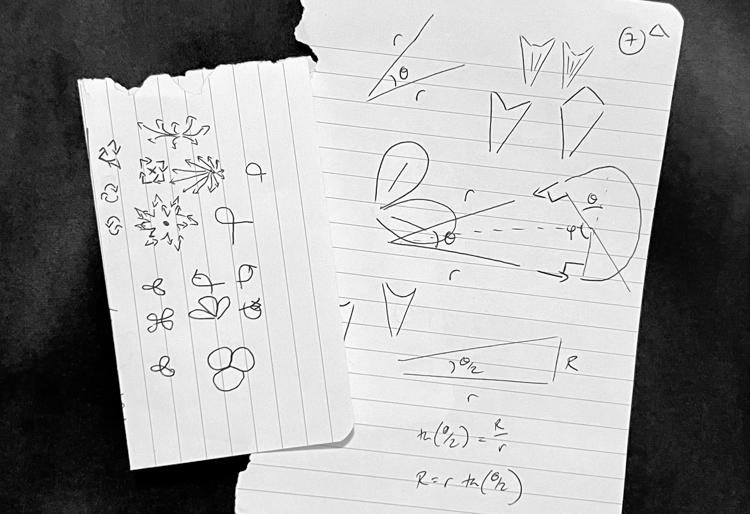 A couple of sheets of paper with various hand-drawn doodles showing simple geometric shapes and circles.