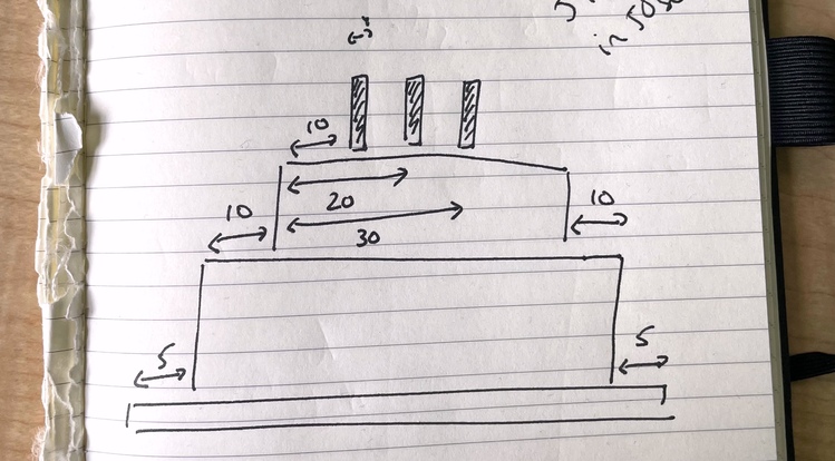 A sketch of some rectangles that loosely resemble a birthday cake, handwritten in a notebook with a few arrows to show various measurements.