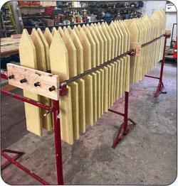 A row of wooden boards which form a triangle point at the end, stacked in a workshop.