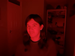A photo of me in a red room. Most of the background has faded to dark red, and my face is glowing red in the middle of the frame.