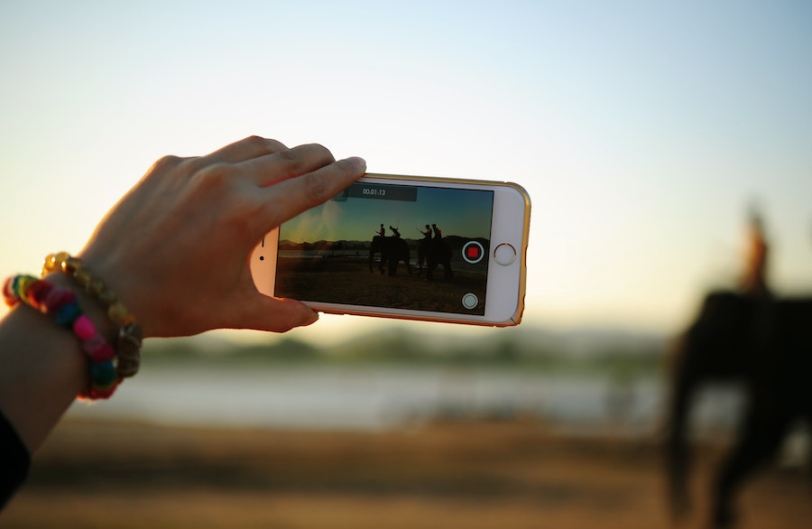 A hand holding up a smartphone recording video.